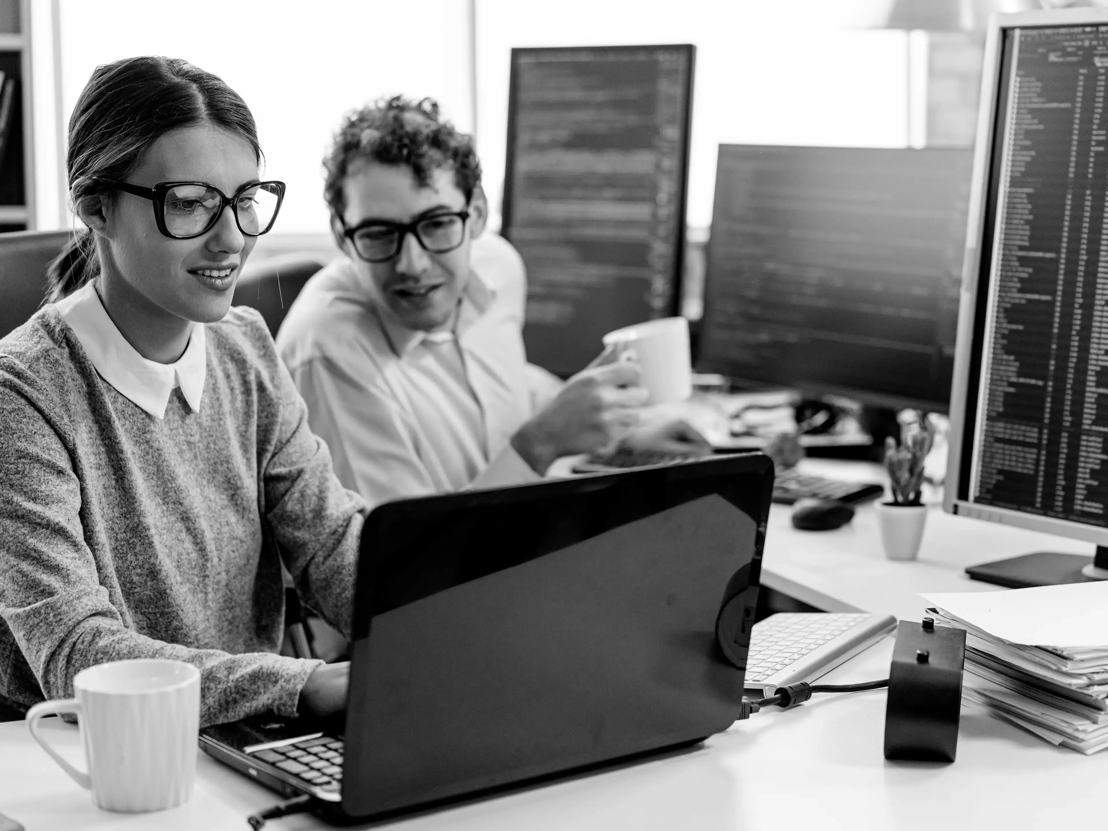 Zwei Kolleg:innen arbeiten gemeinsam am Laptop im Büro