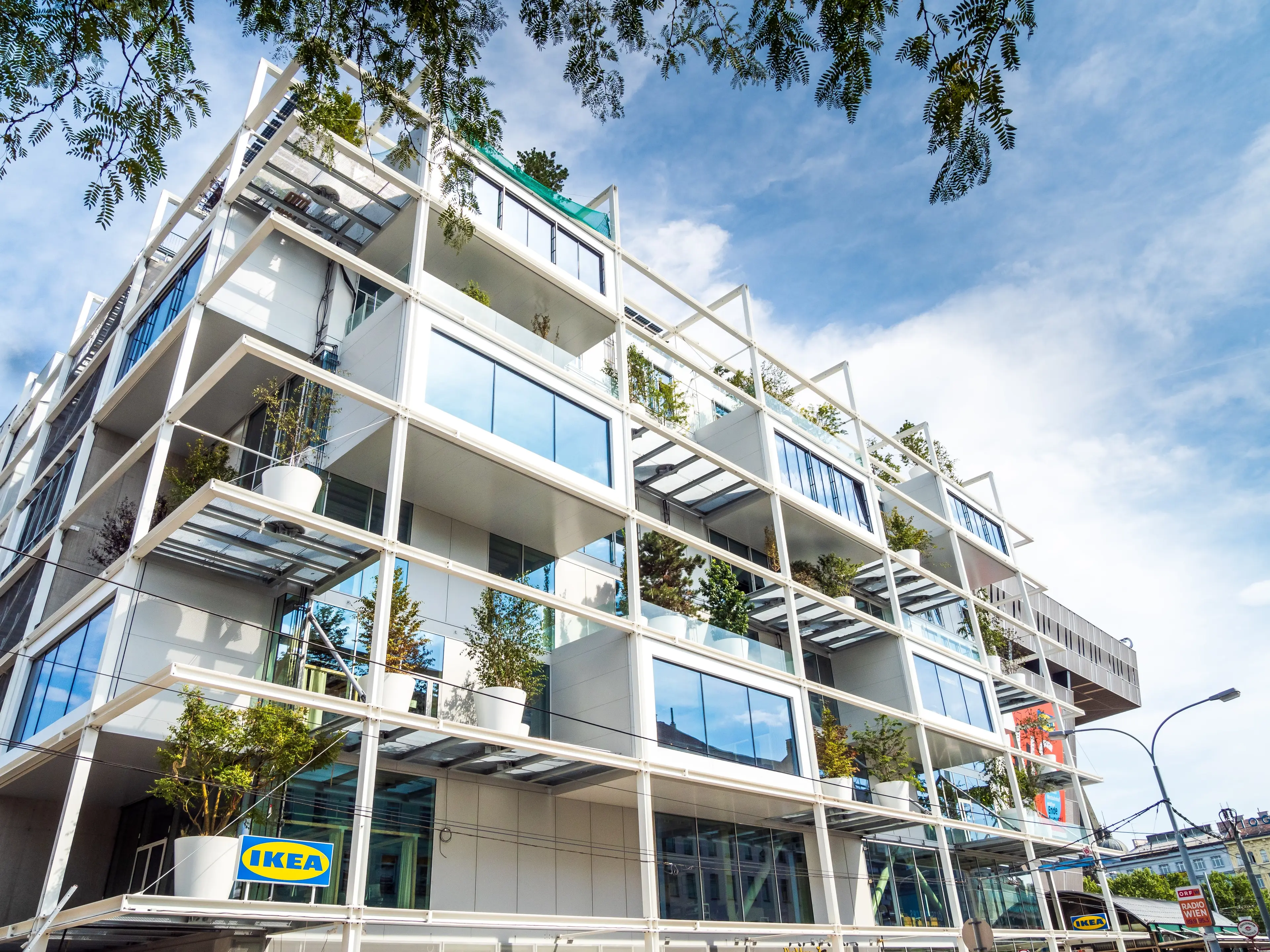 Modernes Wohnprojekt mit Fokus auf Nachhaltigkeit: Innovative Fassadengestaltung mit vertikalen Gärten und großzügigen Terrassen.